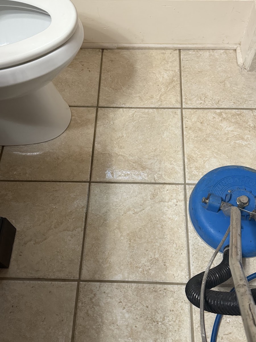 Rotary machine scrubbing tile and grout in a bathroom